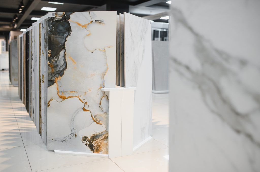 Placas cerâmicas grandes com diferentes acabamentos e padrões expostas em um showroom moderno e bem iluminado.