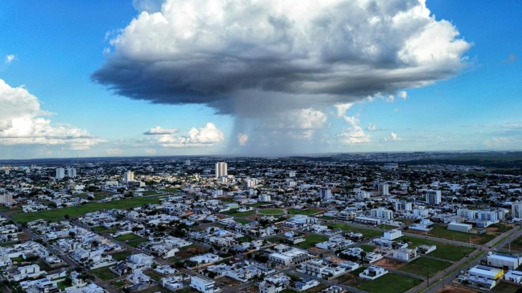 Vista aérea de cidade com chuva localizada caindo de grande nuvem sobre área urbana.
