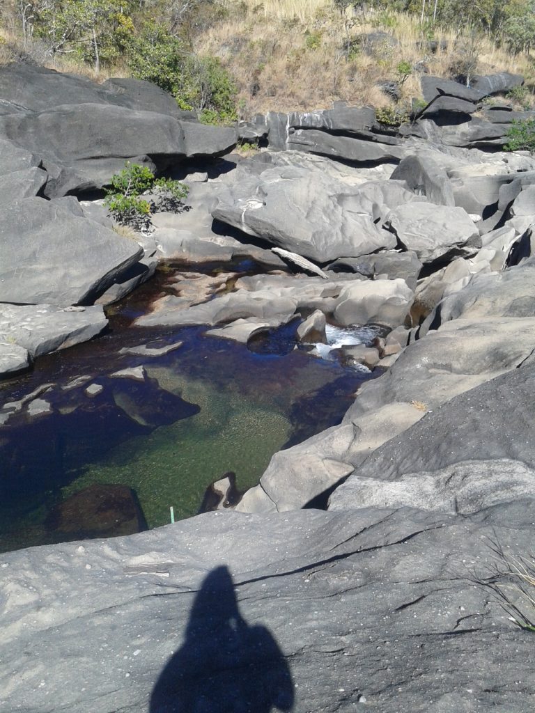 Poço de água entre rochas em área natural.